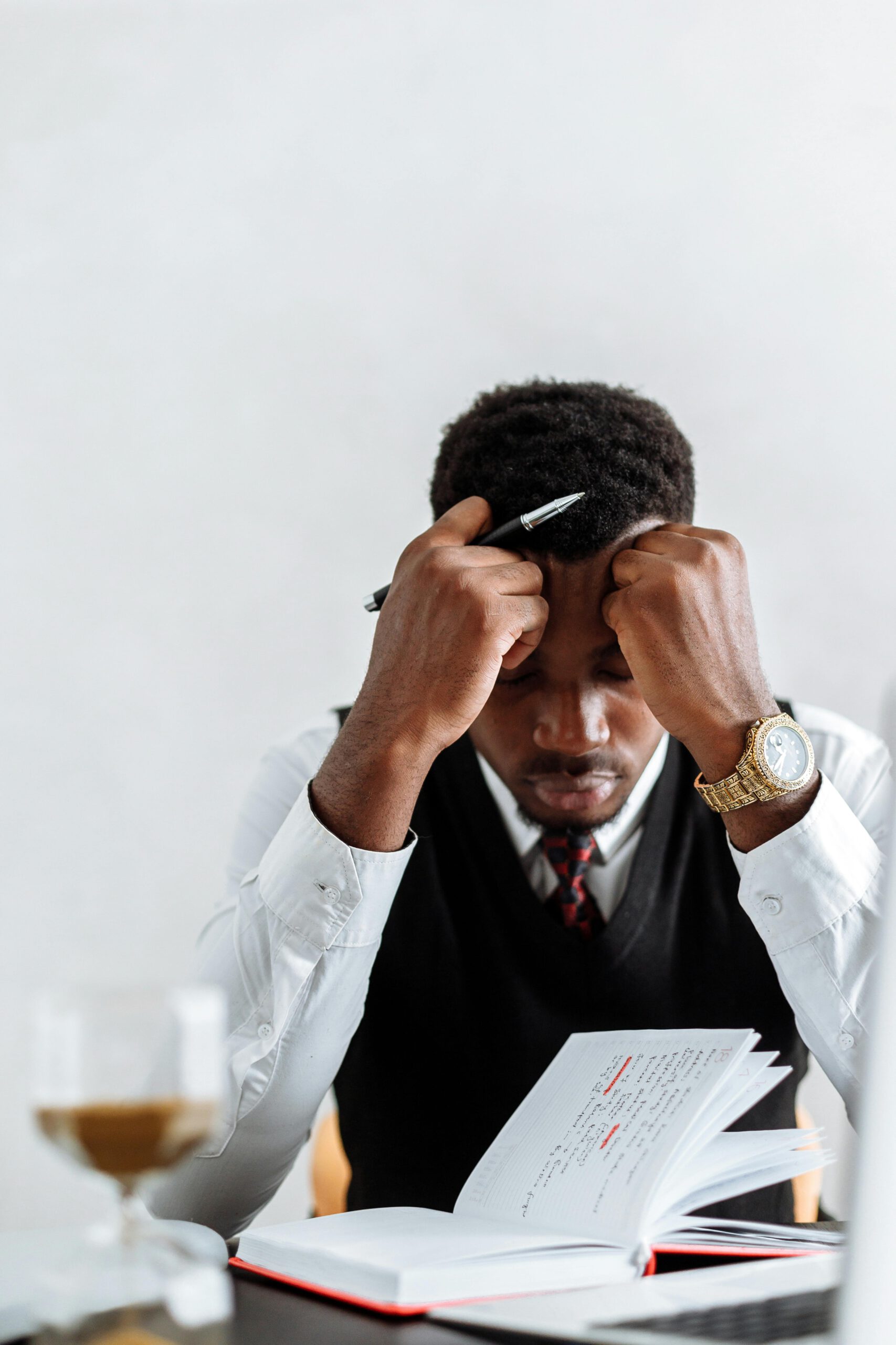 A frustrated businessman sits at a desk reviewing documents, conveying stress and concentration.